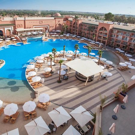 Savoy Le Grand Hotel Marrakech Marakéš Exteriér fotografie The photo shows a large, luxurious hotel resort with a spacious swimming pool at its center. The pool area features several lounge chairs and umbrellas arranged around the water, providing a relaxing atmosphere for guests. Surrounding the pool are la